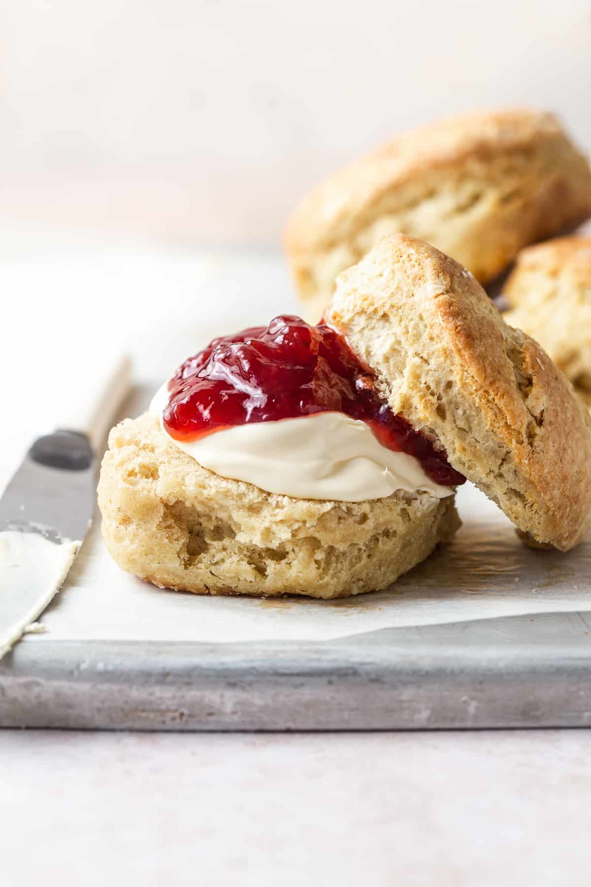 Foolproof scone recipe - scone on a plate served with cream and jam