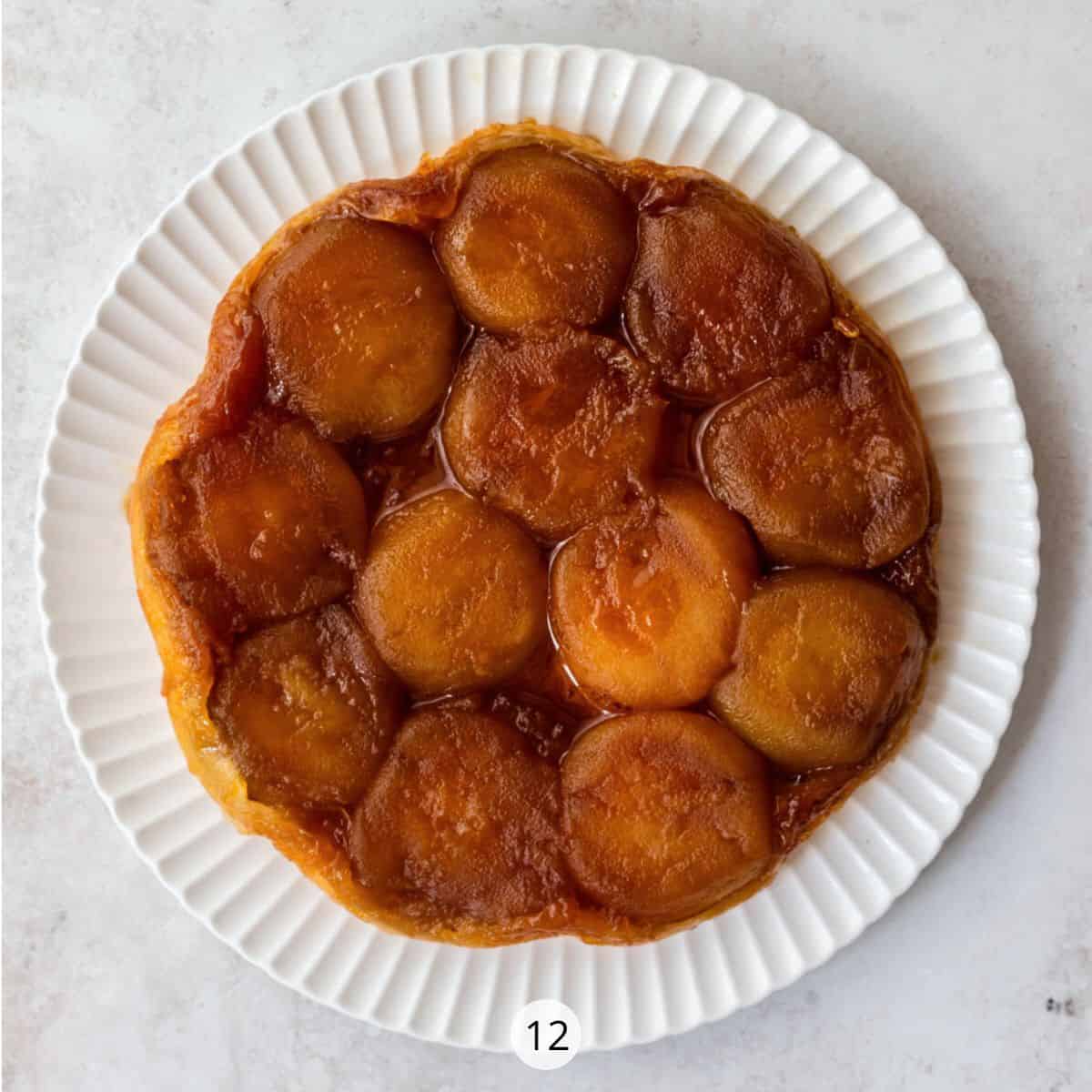 Upside down apple tart on white decorative plate.